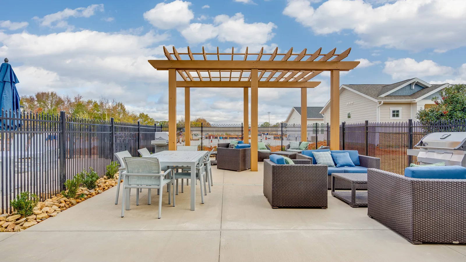 Outdoor seating area privately fenced off from pool for safety with grills, tables and plenty of seating for hosting. New pet-friendly apartment homes for rent with private fenced backyards in Monroe, NC, near Charlotte, NC with pool, dog park, gym, and gated community. *No breed or weight restrictions.