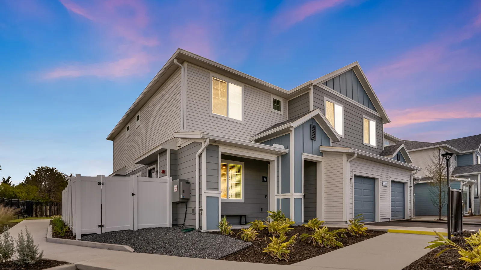 Twilight photo of the front of rental townhome duplex with private backyard. New pet-friendly apartment homes for rent with private fenced backyards in Kissimmee, FL, near Orlando, FL with pickle ball, dog park, gym, and gated community. *No breed or weight restrictions. Yardly Bellalago